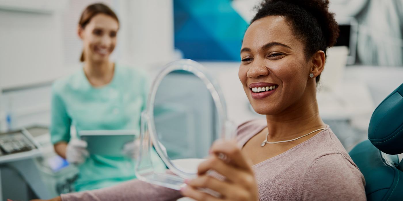 Woman in dental chair viewing her smile in mirror