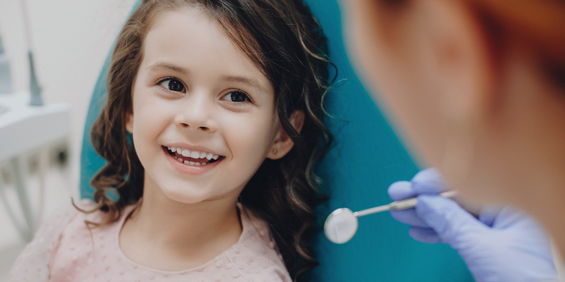 Young girl in dental chair smiling at her dentist